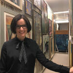 Sonya Jones, Curator of Collections, stands before stored works by Painters 11.