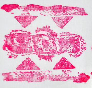 A pink woodblock print on white cotton fabric. The central design contains the imprint of a menstrual pad; it is bordered above and below with other organic geometric forms.